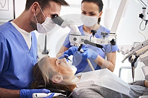 Male dentist working with dental microscope