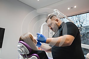 Male dentist working on female patient`s teeth.