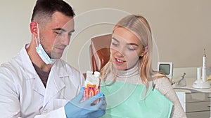 Male dentist working with female patient, showing her tooth mold