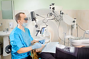 Male dentist working with microscope at modern dentist clinic