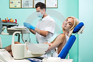 Male dentist. Young blonde girl sitting at the dentist and lookiing at the camera.