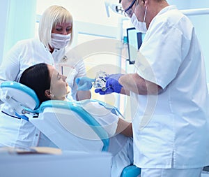 Male dentists examining and working on young female patient.Dentist`s office.