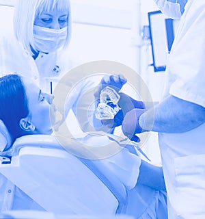 Male dentists examining and working on young female patient.Dentist's office.