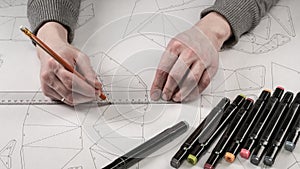 Male designer makes a working drawing. Workplace of a toy designer. Markers, ruler, pen and pencil are on the drawing