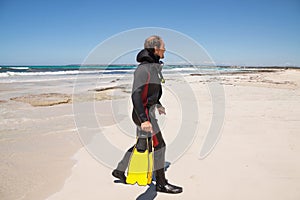 Male diver with diving suit snorkel mask fins on the beach