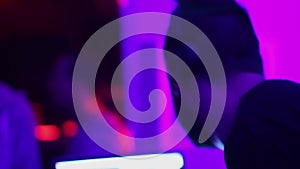 Male DJ in headphones playing music and choosing track on the laptop. Nightclub