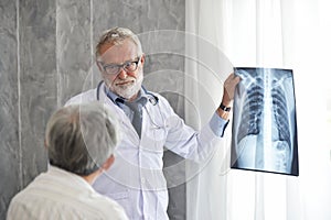 Male doctor and Asian patient are examining x-ray film together.
