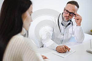 Male doctor asks woman about health complaints during physical examination. Patient at the doctor`s office