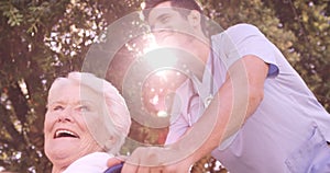 Male doctor assisting senior woman on wheelchair in the backyard