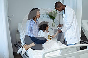 Male doctor attaching pulse oximetry on child patient hand in the ward