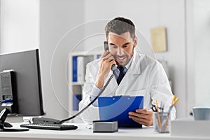 Male doctor calling on desk phone at hospital