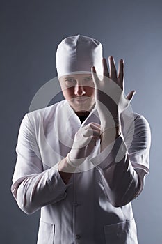 Male doctor in cap with beard wear rubber medical gloves in cont