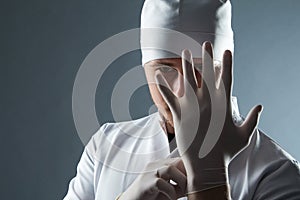 Male doctor in cap with beard wear rubber medical gloves in cont