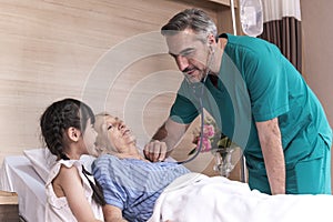 Male doctor check sickness of senior patient on patient bed, beside Lovely girl visit and encourage grandmother in hospital,