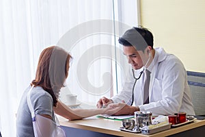 Male doctor checked the patient`s pulse to check the abnormalities of the heart  on the desk