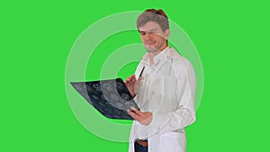 Male doctor checking computed tomography and looking at camera approvingly on a Green Screen, Chroma Key.