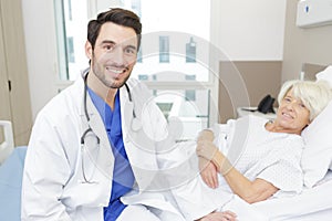 male doctor checking senior female patient woman in hospital bed