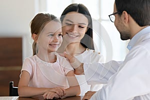 Male doctor cheer small girl patient at hospital consultation