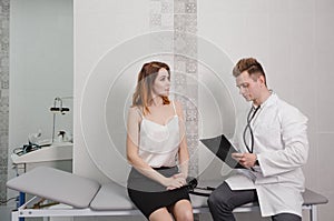 a male doctor communicates with a patient by recording readings while sitting on a couch in the office.