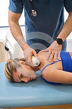 Male doctor conducting extracorporeal shockwave therapy to female patient