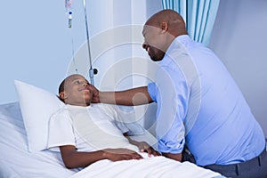 Male doctor consoling patient during visit in ward