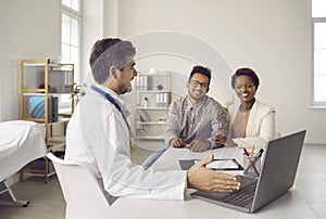 Male doctor consult ethnic couple at clinic