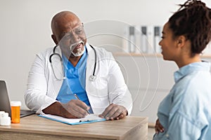 Male doctor consulting young smiling pregnant woman, writing record