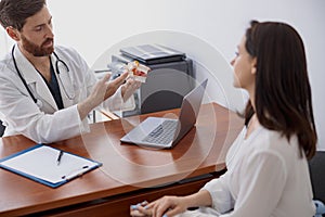 Male doctor consults patient and shows the model of several spines in modern clinic