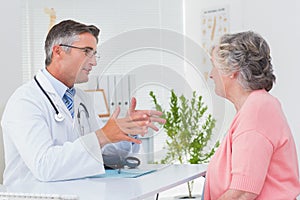 Male doctor conversing with female patient at table