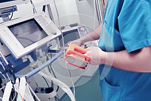 Male doctor with defibrillator electrodes in his hand sets the d