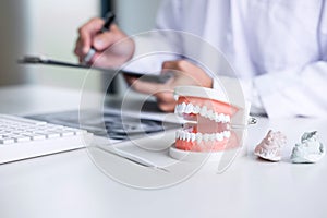 Male doctor or dentist writing report working with tooth x-ray f