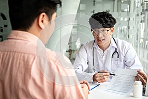 Male doctor discussing with the patient explaining symptoms of the disease after diagnosis checking while recommending treatment