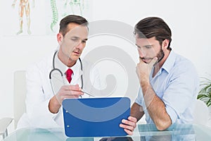 Male doctor discussing reports with patient at desk
