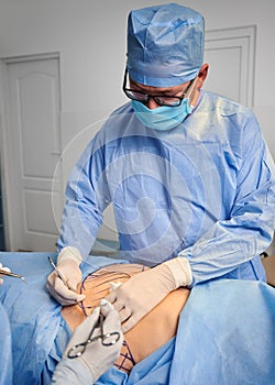 Male doctor doing plastic surgery in operating room.