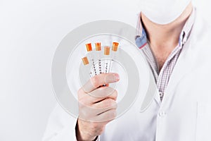 Male doctor endocrinologist in mask holding five insulin syringes on white background