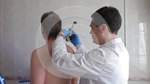A male doctor examines the patient`s skin using an electronic medical device. Medical technology.4K