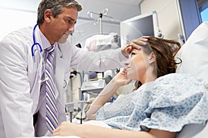 Male Doctor Examining Female Patient In Emergency Room