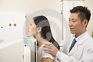 Male Doctor Examining Female Patient's Mid Section With X-ray Machine