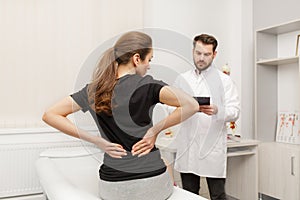 Male doctor examining female patient suffering from back pain. Medical exam. Chiropractic, osteopathy, post traumatic
