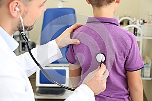 Male doctor examining little child with stethoscope