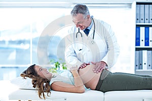 Male doctor examining pregnant woman in clinic