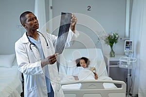 Male doctor examining x-ray report in the ward