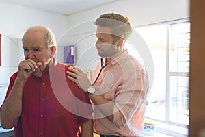 Male doctor examining a senior patient thanks to a stethoscope