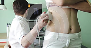 Male doctor examining the woman`s right kidney using an ultrasound scanner.