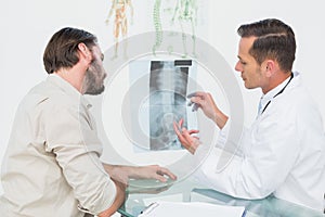 Male doctor explaining spine xray to patient