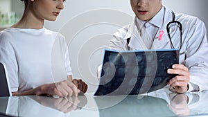 Male doctor explaining young lady results of mammogram, breast cancer awareness photo