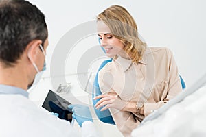 Male doctor and female patient looking at tablet screen in modern