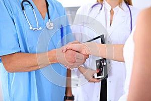 Male doctor and female patient shaking hands. Partnership, trust and medical ethics concept