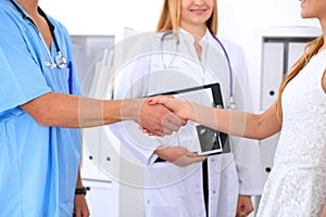 Male doctor and female patient shaking hands. Partnership, trust and medical ethics concept
