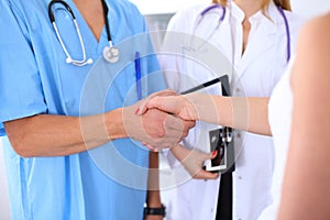 Male doctor and female patient shaking hands. Partnership, trust and medical ethics concept